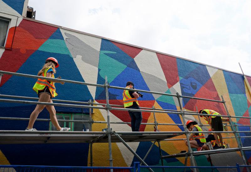 In a back alley near 3rd Street &amp; Lonsdale Avenue, a group of youth have been transforming an old wall into a painted mural full of colour and history