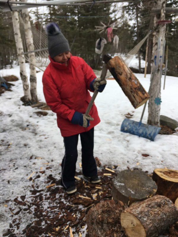 Margaret Nazon chops wood outside her home.