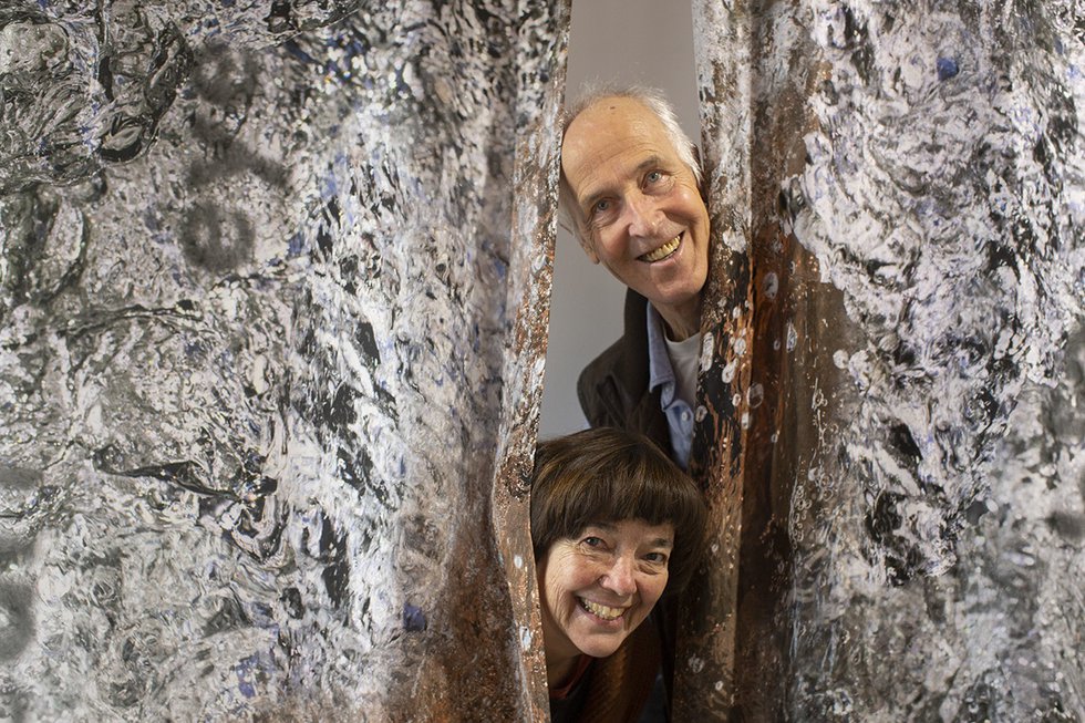 Liz Ingram and Bernd Hildebrandt peek out from behind a work at their exhibition, "Touching Gravitas," at the SNAP Gallery in Edmonton. (photo by Manpreet Singh)