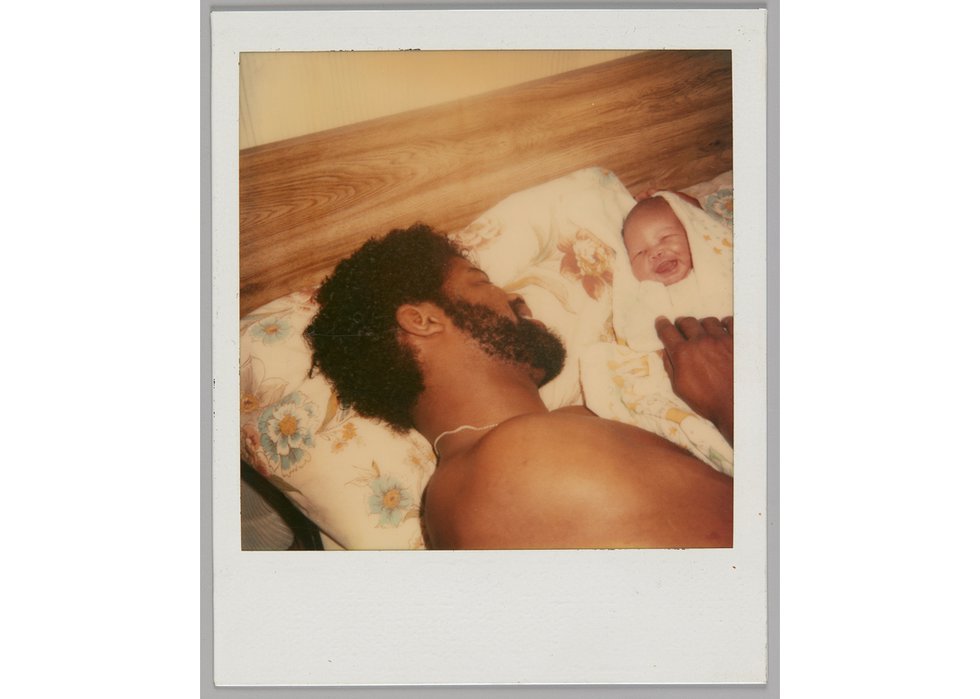 Unknown photographer, “[Man lying in bed with a smiling baby],” 1981-1991