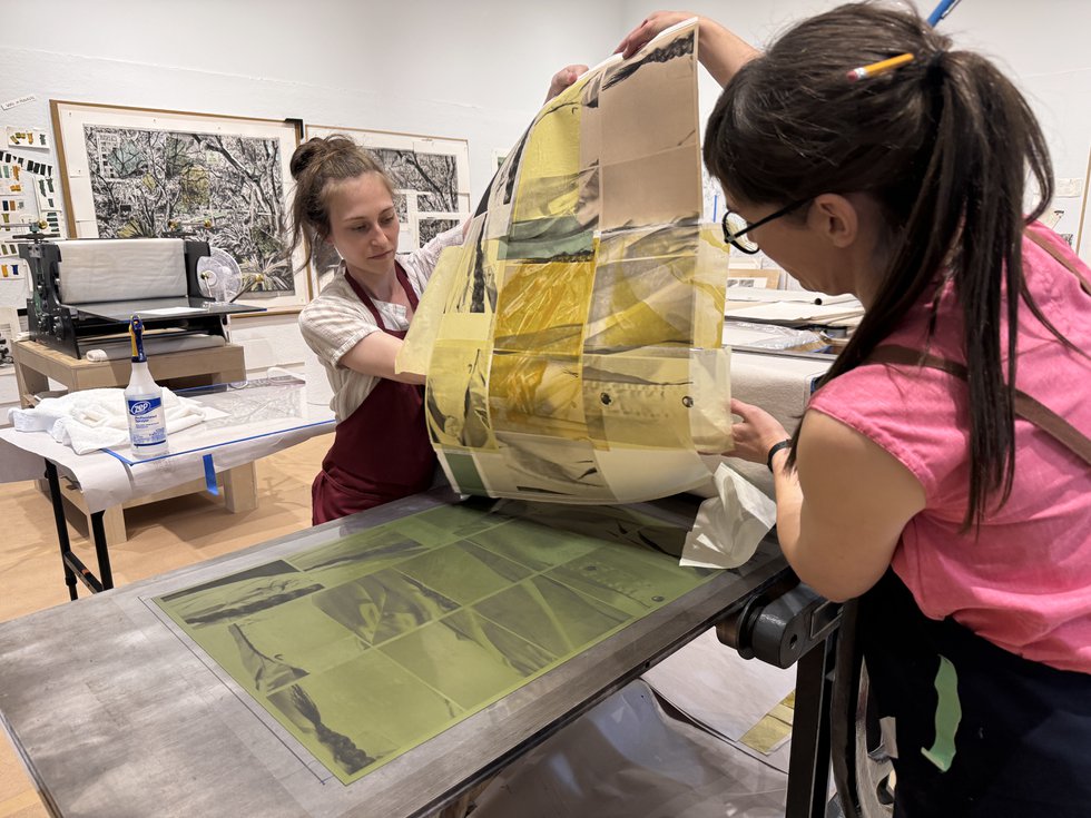 Printer Sarah Madgin, left, and Jillian Ross, right, pull a test print for Wally Dion during the Live Editions/Jillian Ross Print residency at the Remai Modern in Saskatoon, Sask. (photo by Nasibeh Nasibi)